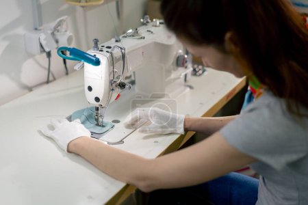 Foto de Profesional de la tintorería de una chica joven dobladillos de un parche en un suéter con una máquina de coser - Imagen libre de derechos
