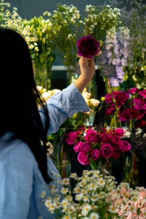Téléchargez les photos : Boutique de fleurs une fille près du comptoir avec des fleurs choisit les fleurs nécessaires et un arrangement de fleurs - en image libre de droit