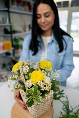 Téléchargez les photos : Dans un magasin de fleurs une fille près d'une table blanche recueille un arrangement de fleurs de jonquilles jaunes - en image libre de droit
