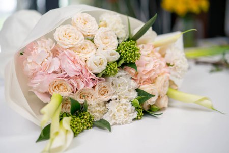 close-up in a flower shop on a white table lies a ready-assembled gently pink bouquet as a gift for your beloved