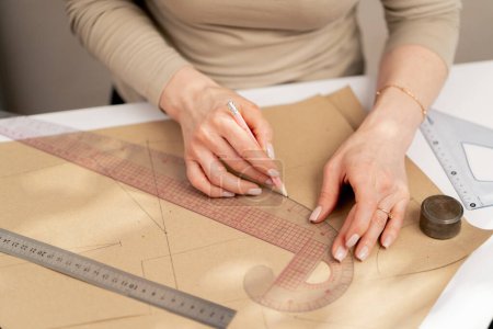 Photo for Close up A professional seamstress works with kraft paper to draw future patterns for a dress - Royalty Free Image