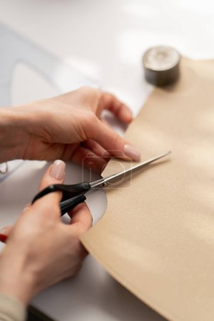 Photo for Close up A professional seamstress works with craft paper to cut out future patterns for a dress - Royalty Free Image