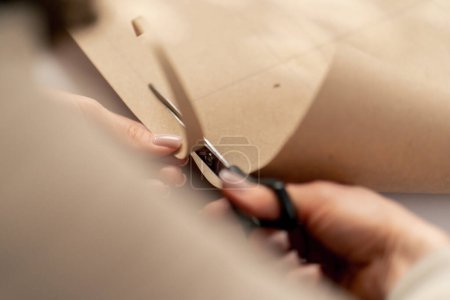 Photo for Close up A professional seamstress works with craft paper to cut out future patterns for a dress - Royalty Free Image