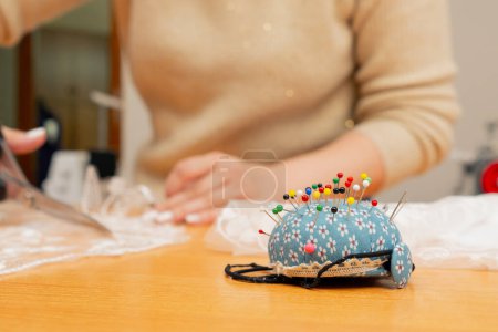 Photo for Close up in the sewing workshop a young woman works with lace and cuts out the desired shape - Royalty Free Image