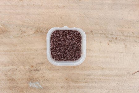 Chocolate Meses in a plastic container on a wooden background
