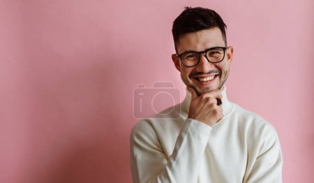 Téléchargez les photos : Portrait of happy bearded man wearing eyeglasses laughing and looking camera while posing isolated over pink background. People emotions concept - en image libre de droit