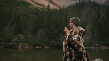 Téléchargez les photos : Satisfied woman backpacker drinking hot tea and relaxing in the mountains nature on autumn day. Beautiful mountain landscape view - en image libre de droit