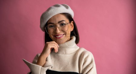 Téléchargez les photos : Studio shot de fille française incroyable en béret et lunettes souriant isolé sur fond rose. Concept de style français - en image libre de droit