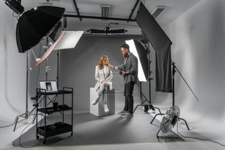 Téléchargez les photos : Photographe professionnel et beau modèle sur le tournage de mode en studio photo avec équipement d'éclairage. Concept d'occupation - en image libre de droit