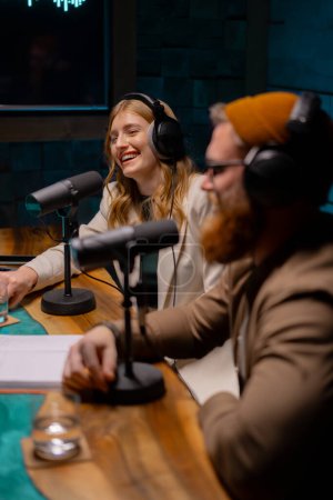 Téléchargez les photos : Un homme et une femme sont assis devant des microphones dans un studio, souriant. Concept de studio Podcast. - en image libre de droit