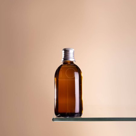 Botella de vidrio marrón con tapa plateada burla ap sobre un fondo beige. Concepto anti envejecimiento, ácido hialurónico y colágeno con péptidos