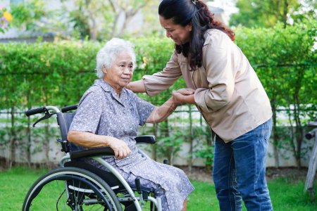 Téléchargez les photos : Aide soignant asiatique femme âgée handicapée patient assis sur un fauteuil roulant dans le parc, concept médical. - en image libre de droit
