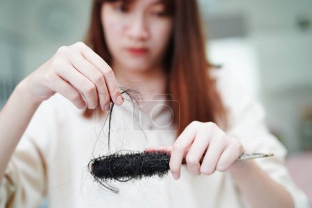 Téléchargez les photos : Asian woman have problem with long hair loss attach to comb brush. - en image libre de droit
