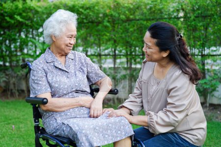 Téléchargez les photos : Aide soignant asiatique femme âgée handicapée patient assis sur un fauteuil roulant dans le parc, concept médical. - en image libre de droit