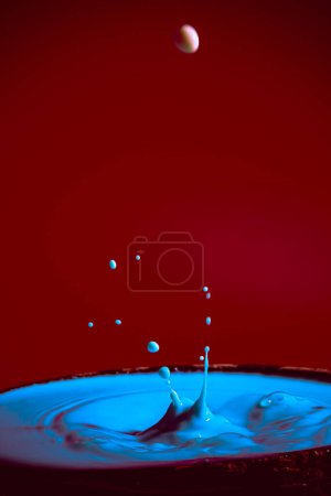 Foto de Colisión de las gotas de agua en movimiento de color azul sobre un fondo rojo púrpura formando figuras y olas al caer y chocar entre sí fotografía e imágenes de alta resolución relajación fotografía - Imagen libre de derechos
