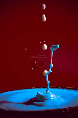 Foto de Colisión de las gotas de agua en movimiento de color azul sobre un fondo rojo púrpura formando figuras y olas al caer y chocar entre sí fotografía e imágenes de alta resolución relajación fotografía - Imagen libre de derechos