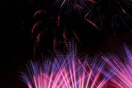 Foto de Feliz año nuevo fiestas de año nuevo fuegos artificiales de colores víspera de año nuevo en la pirotecnia en el oscuro cielo negro de la noche con la imagen de cohetes de colores reflejados en el agua de un lago festividades de luz - Imagen libre de derechos