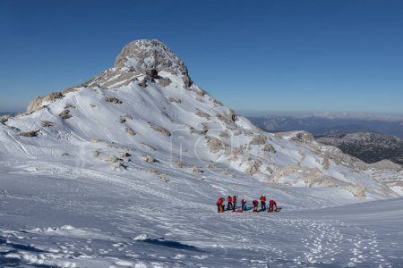 Foto de Un grupo de escaladores en equipo rojo están entrenando en una ladera nevada cerca de uno de los picos en la región de Dachstein, Alpes austríacos. Foto de alta calidad - Imagen libre de derechos