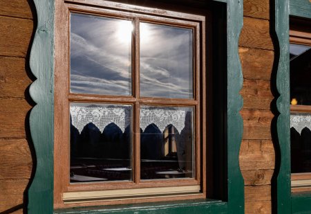 Photo pour Mountain hut window reflecting dramatic cloudy sky, Austria. High quality photo - image libre de droit