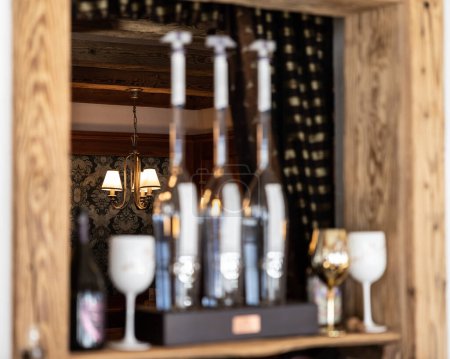 Téléchargez les photos : Vue d'une lampe sur fond de bouteilles et de verres dans la fenêtre intérieure d'un restaurant de montagne autrichien. Photo de haute qualité - en image libre de droit