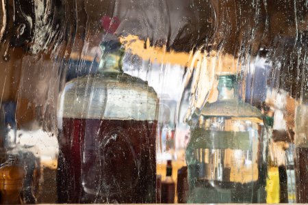 Téléchargez les photos : Grandes bouteilles de clair de lune derrière un verre opaque ajouré dans un restaurant alpin, en Autriche. Photo de haute qualité - en image libre de droit