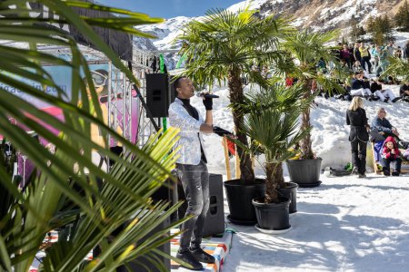 Photo for AUSTRIA, SPORTGASTEIN - March 18, 2023: Event Palmen auf den Almen, musician sings against the backdrop of palm trees. High quality photo - Royalty Free Image