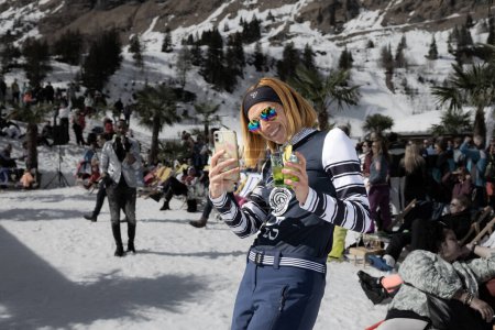 Photo for AUSTRIA, SPORTGASTEIN - March 18, 2023: Event Palmen auf den Almen, girl filming what is happening on the phone. High quality photo - Royalty Free Image