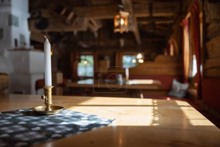 Téléchargez les photos : Bougie sur la table. illuminé par la lumière du soleil, à l'intérieur d'un restaurant alpin, en Autriche. Photo de haute qualité - en image libre de droit