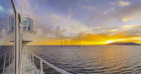 Photo for Binoculars on the deck of a cruise ship as it sails off into the sunset. - Royalty Free Image
