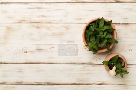 Foto de Wooden bowl and mortar pestle with melissa on wooden background, top view. - Imagen libre de derechos