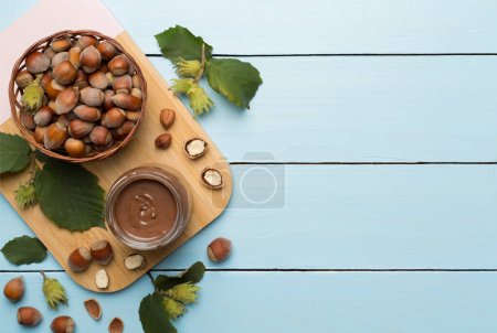 Téléchargez les photos : Crème aux noisettes avec noix et feuilles vertes sur fond bois, vue de dessus. - en image libre de droit