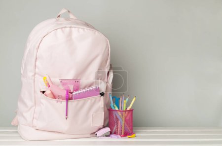 Foto de Mochila escolar rosa con papelería en mesa de madera - Imagen libre de derechos