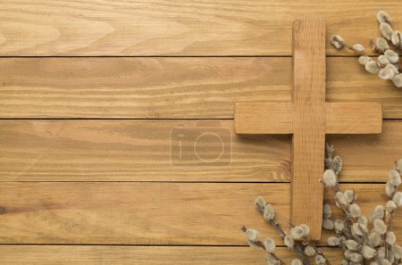 Cross with willow branches on wooden background, top, view. Palm Sunday concept