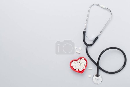 Photo for Stethoscope with heart medicines on color background, top view - Royalty Free Image