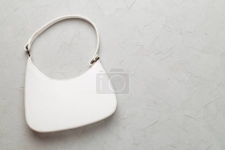 Trendy woman bag on concrete background, top view