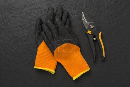 Secateurs and gloves on concrete background, top, view