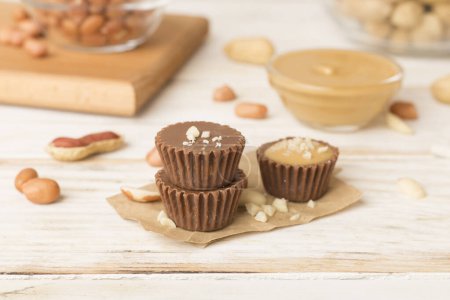 Foto de Sabrosas tazas de mantequilla de cacahuete de chocolate en la mesa de madera - Imagen libre de derechos