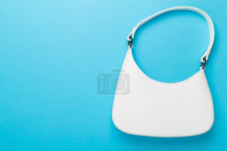 Trendy woman bag on color background, top view