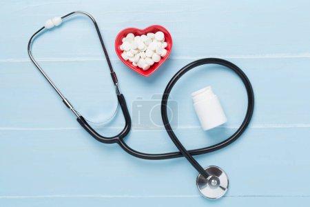 Stethoskop mit Herzmedikamenten auf Holzgrund, Draufsicht