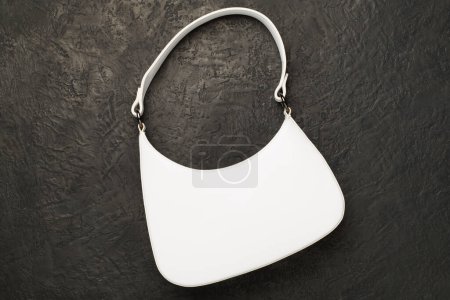 Trendy woman bag on concrete background, top view