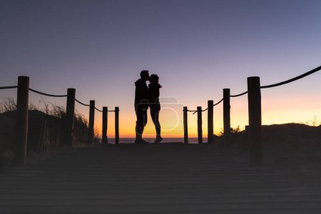 Photo for Silhouette of man and woman couple kissing at a beautiful sunset on the beach. - Royalty Free Image