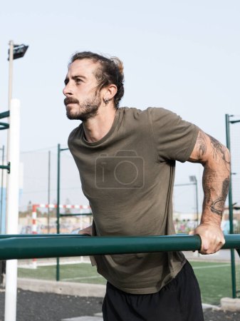 Photo for Caucasian man with tattoos doing triceps exercise outdoor at the calisthenics park - Royalty Free Image
