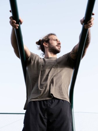 Photo for Caucasian calisthenics athlete with long hair and beard at the parallel bars - Royalty Free Image