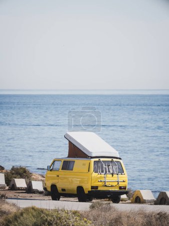 Téléchargez les photos : Camion camping-car vintage jaune avec toit ouvrant garé au bord de la mer - en image libre de droit