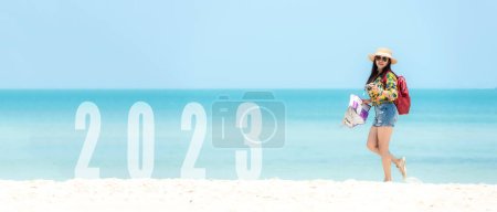 Téléchargez les photos : Asiatique jeune femme heureux saut félicitations et célébrer en bonne année 2023 pour changer nouveau concept de vie future. Liberté style de vie saut dans le cadre du numéro 2023 succès sur la plage de sable en plein air, espace de copie pour bannière - en image libre de droit