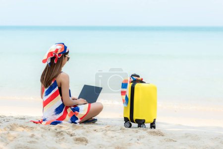 Téléchargez les photos : Lifestyle femme freelance en utilisant un ordinateur portable travaillant sur la plage. Asiatiques succès et ensemble votre passe-temps de travail et de réunion conférence sur Internet en vacances - en image libre de droit