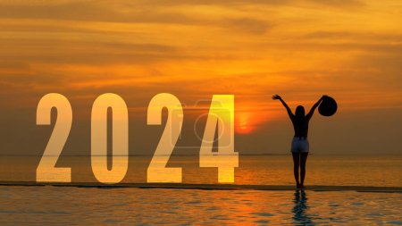 Téléchargez les photos : Bonne année 2024 carte. Silhouette style de vie femme yoga lever le bras debout dans le cadre du numéro 2024 près de la plage au coucher du soleil. Concept sain et vacances - en image libre de droit