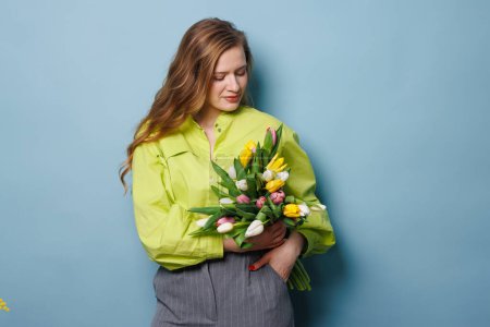 girl with a spring bouquet of tulips on a clean blue background, spring flowers