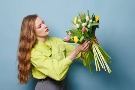 chica con un ramo de primavera de tulipanes sobre un fondo azul limpio, flores de primavera