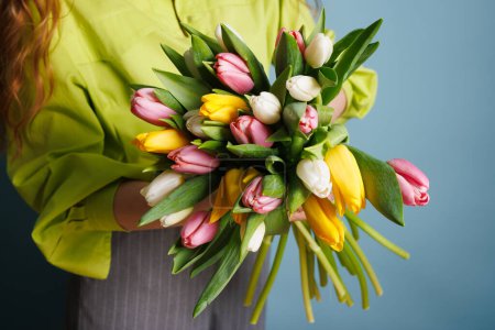 fille avec un bouquet de printemps de tulipes sur un fond bleu propre, fleurs de printemps